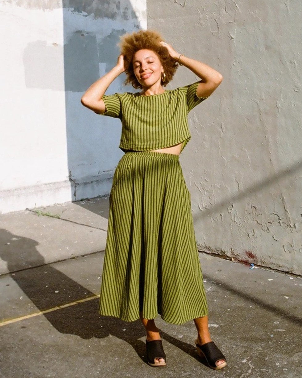 Curator Fawn avocado green stripe skirt at Clad, a sustainable clothing boutique in Asheville, NC. Paired with the matching Hanna top and black leather slides.