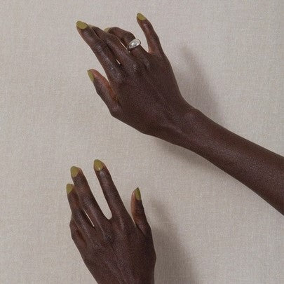 Non-toxic, cruelty-free nail polish in a muted chartreuse Eames green on hands.