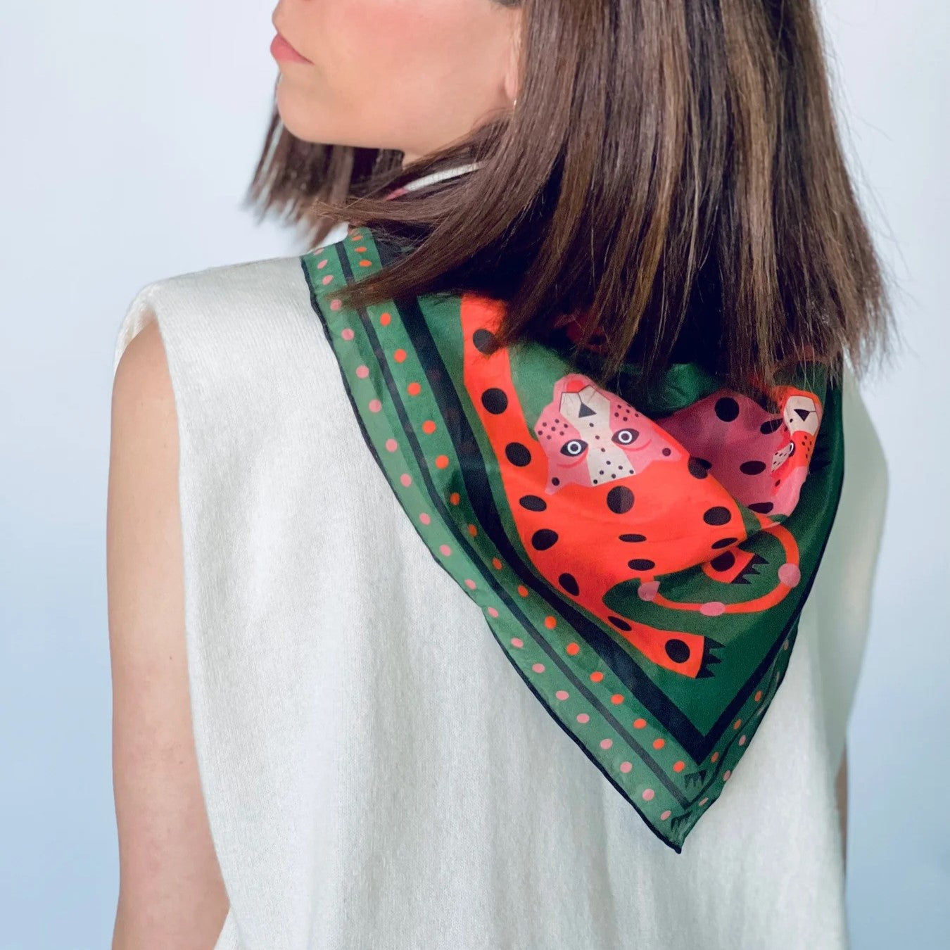 Silk and cotton cheetah print bandana with green background and pink and poppy orange red cheetahs at Clad, a sustainable clothing shop in Asheville, NC.