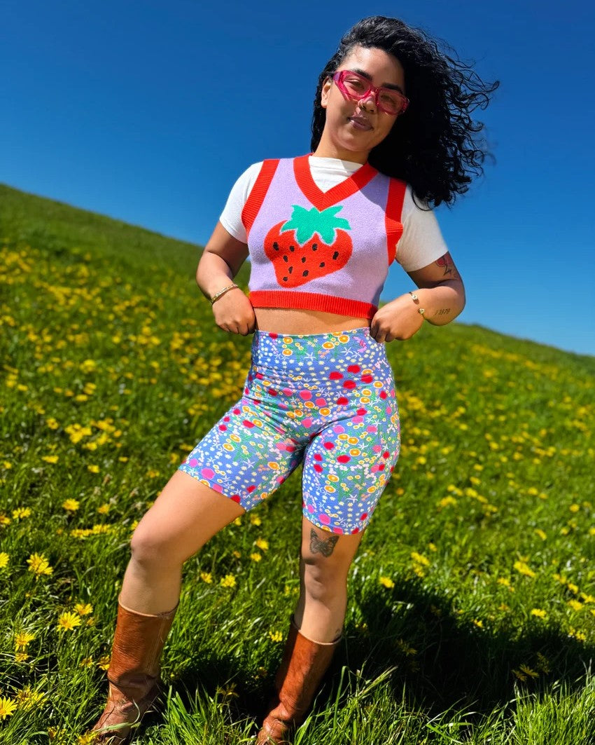 Nooworks Bike Shorts Super Bloom at Clad, a sustainable clothing store in Asheville, NC. Paired with a red and lavender strawberry vest in a meadows with daisies and blue sky.