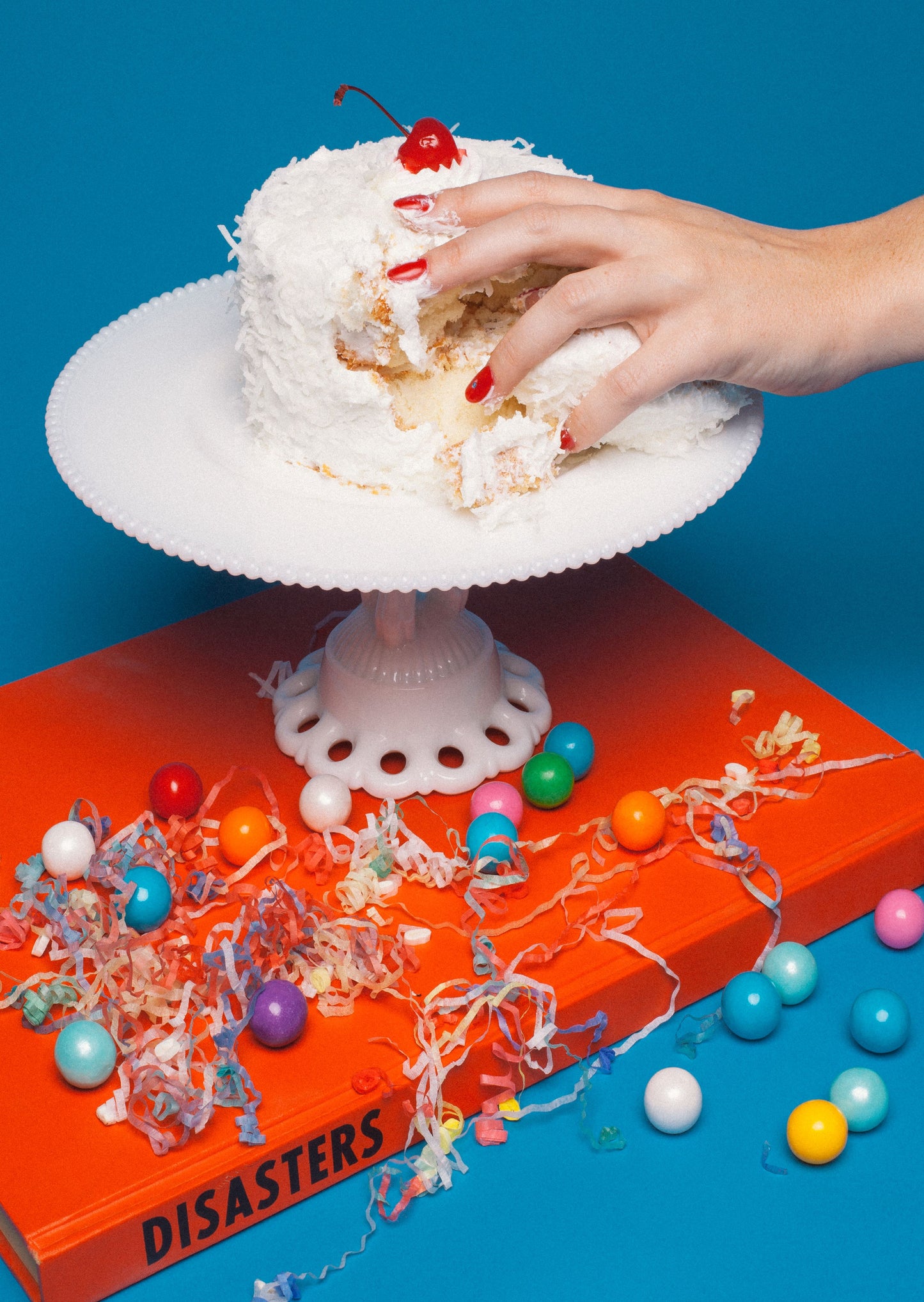 1000 piece colorful puzzle with a hand grabbing cake on top of a book Disasters. Red and blue in color.