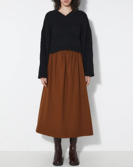 Tobacco brown Fisher Skirt from Rita Row at Clad, a sustainable clothing boutique in Ashevile, NC. Paired with a black v-neck sweater and chestnut leather boots.