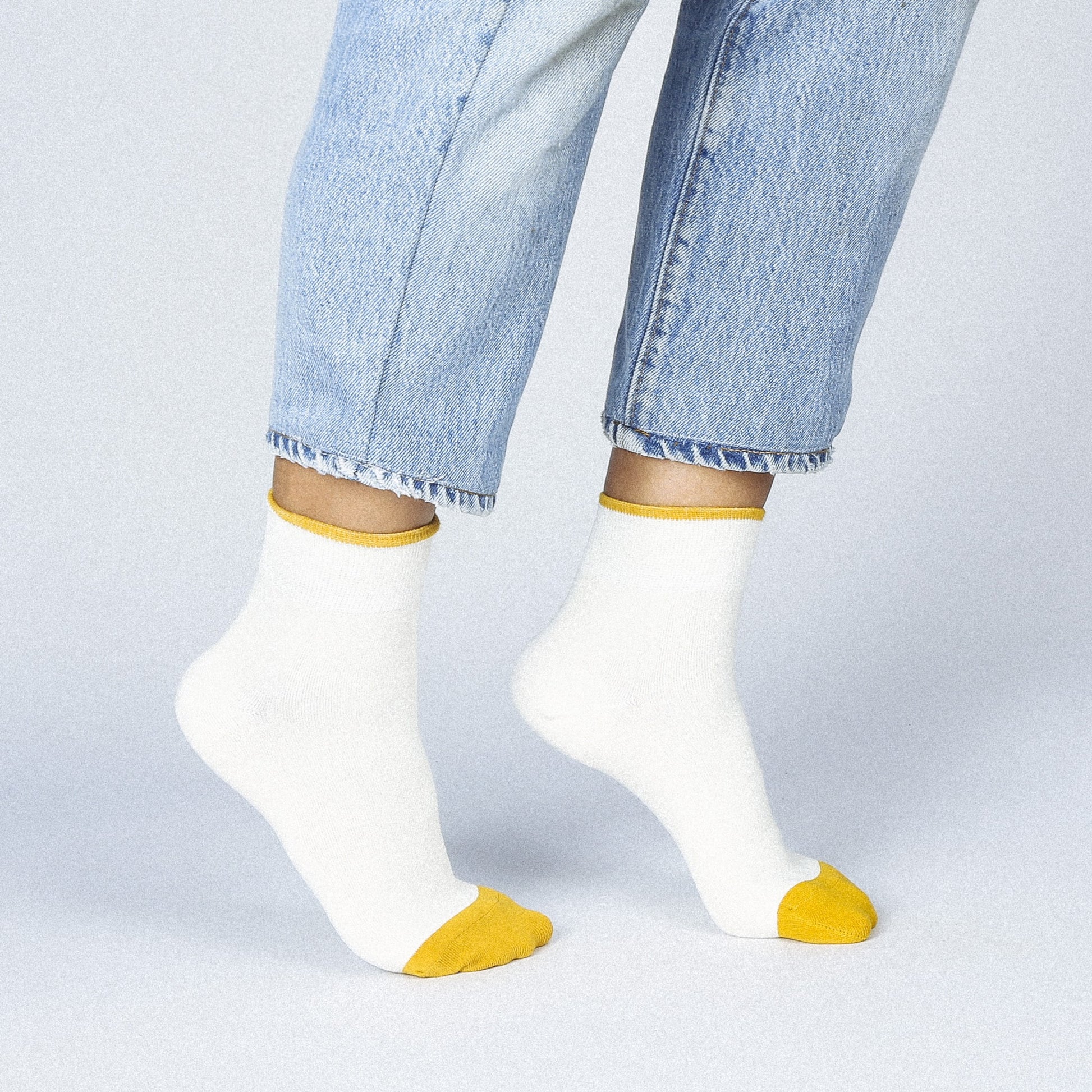 A creamy white ankle sock with gold yellow toes and hem.