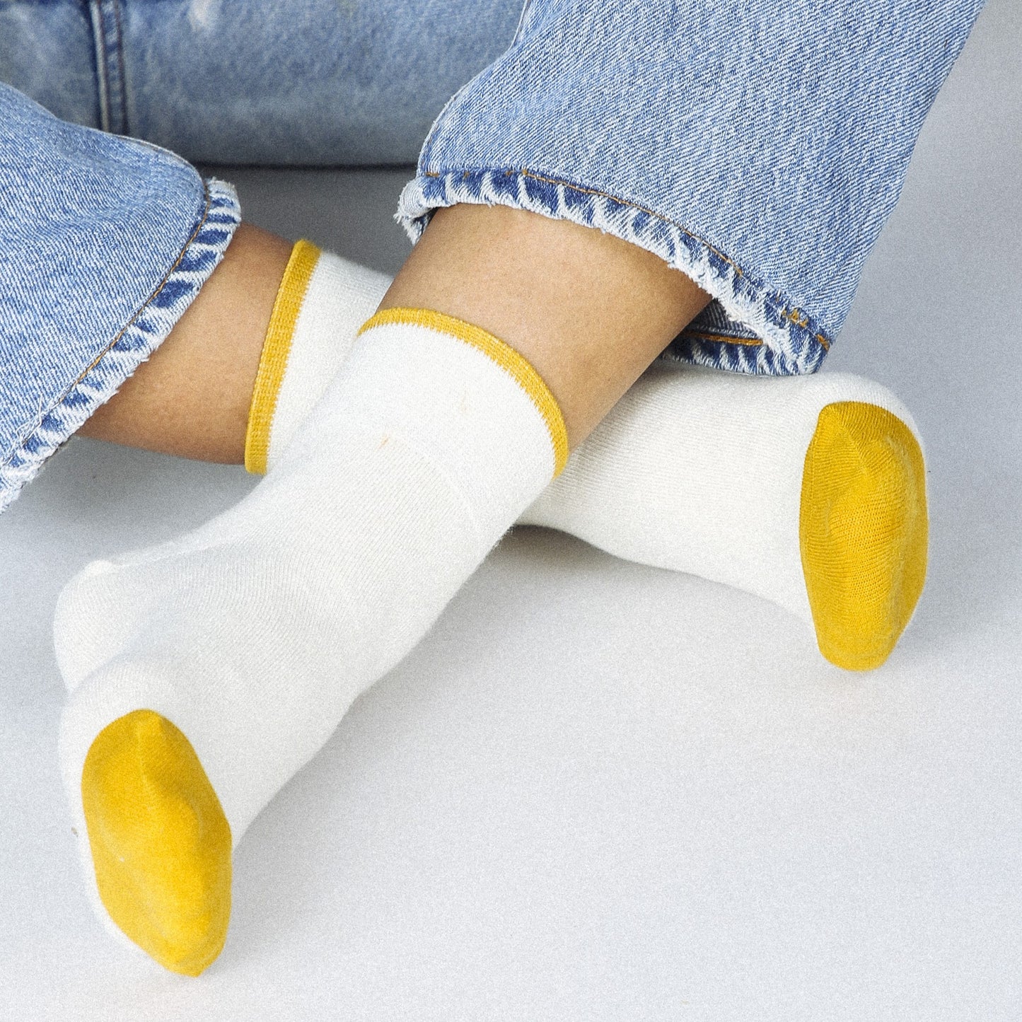 A creamy white ankle sock with gold yellow toes and hem.