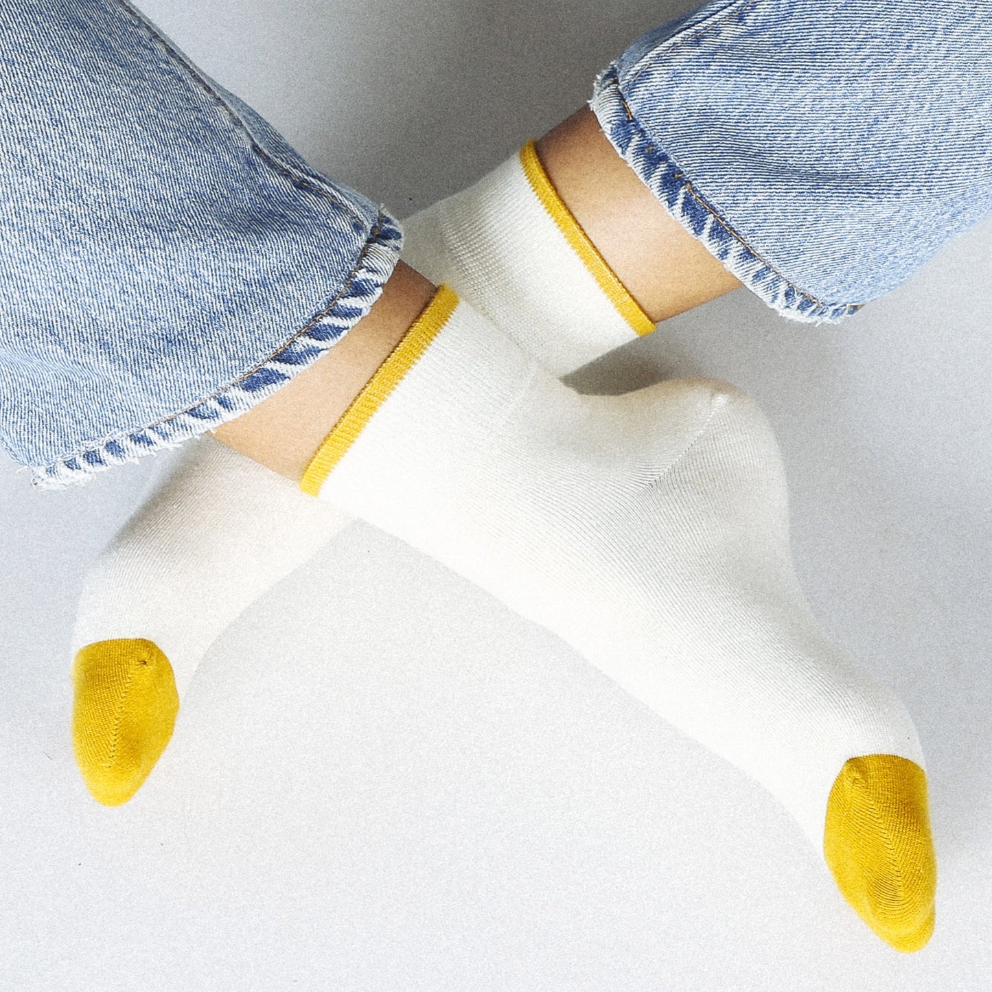 A creamy white ankle sock with gold yellow toes and hem.
