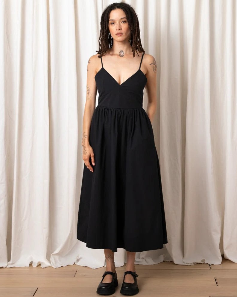 Black tie back midi dress by Ali Golden with a fitted v-neck bodice, adjustable spaghetti straps, and fully lined. Paired with chunky black loafers.