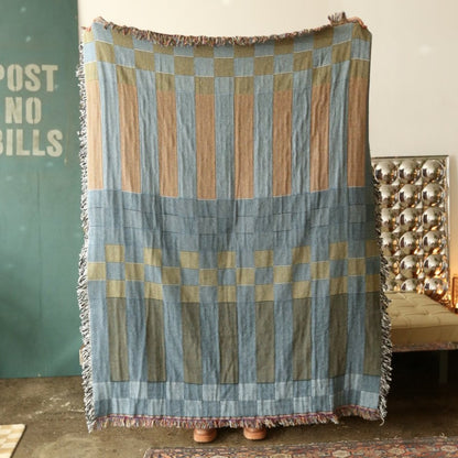 A checkered, reversible tapestry blanket with stripes and fringe.