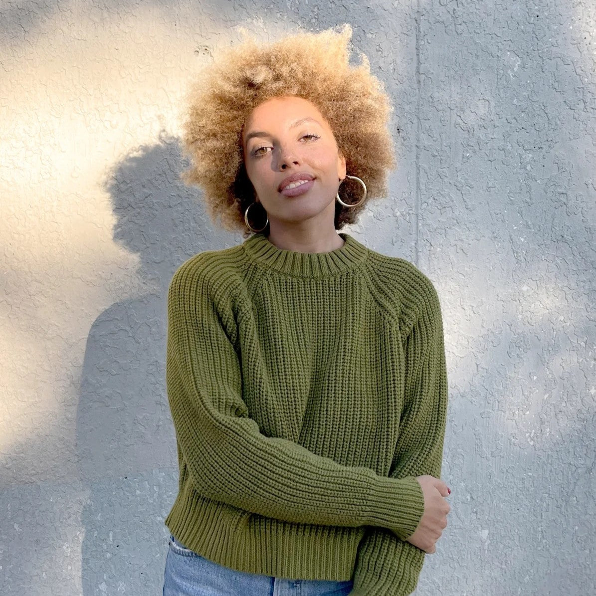 Avocado green cropped knit Sonnie Sweater by Curator in San Francisco, California. Paired with large gold hoops.