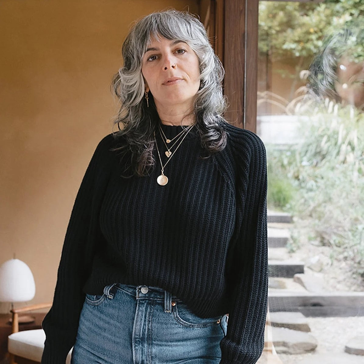 Black knit Sonnie Sweater from Curator San Francisco, California. Paired with layered necklace chains and high-waisted blue denim jeans.