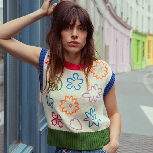 Wildflower Knit Vest by Gorman made with organic cotton. Green and red ribbed hems with blue ribbed cap sleeves. Abstract shapes on a cream background in purple, orange, red, green, and blue.