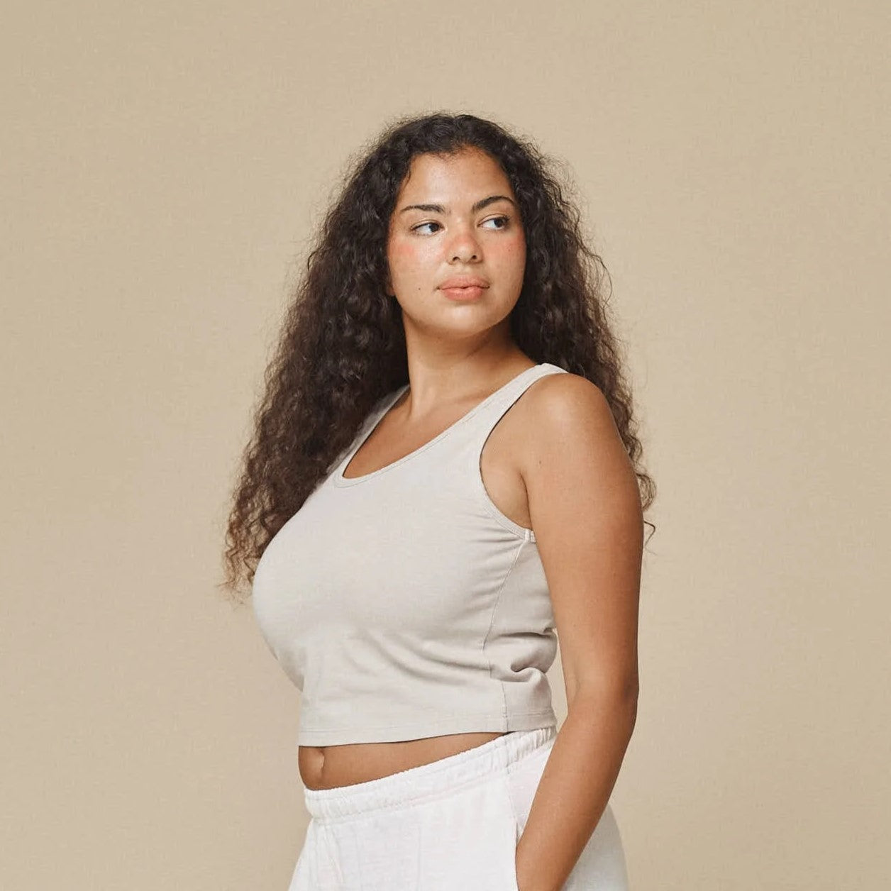 A washed white stretchy fitted scoopneck tank made of a cotton hemp blend on model.