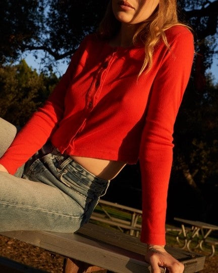 Bright red button-down long sleeve cardigan. Cropped and paired with high-wasited denim jeans.