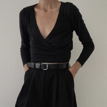 Black long sleeve ballet wrap top by LAUDE the Label. Paired with black high-waisted pants and a black leather belt.