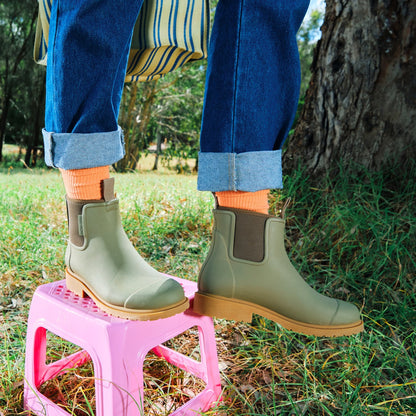 Khaki olive green Bobbi Rain Boot by Merry People at Clad, a sustainable clothing shop in Asheville, NC. Paired with cuffed blue jeans.