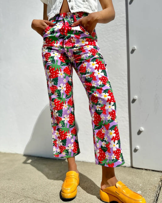 An ankle-length floral and berry printed wide leg pant in lilac lavender and red strawberries. Made in California by women-owned business Nooworks. Belt loops, pockets, zipper closure.