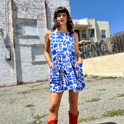 Blue and white abstract floral pattern Dutch Garden in a mini loose Big Pocket Dress by woman-owned brand Nooworks in California. Paired with red cowboy boots.