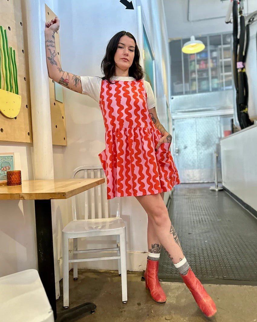 Pink Squiggle Big Pocket Dres sby Nooworks in Clad, a sustainable clothing boutique in Asheville, North Carolina. Paired with red cowboy boots.