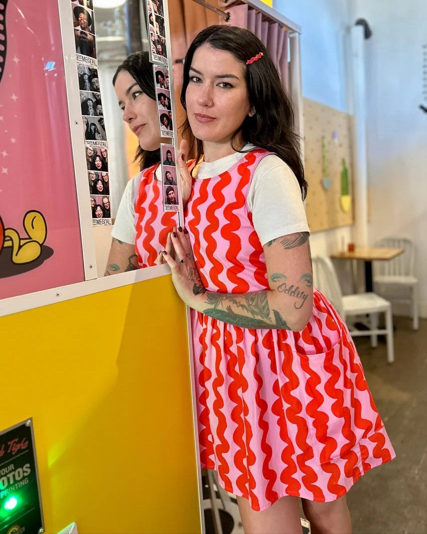 Pink Squiggle Big Pocket Dres sby Nooworks in Clad, a sustainable clothing boutique in Asheville, North Carolina. Paired with red cowboy boots.