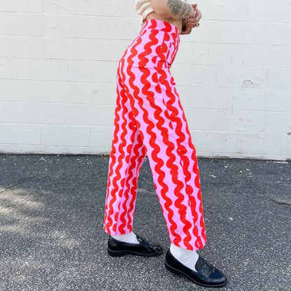 Nooworks pink squiggle casual bell pant with red at Clad, a sustainable clothing store in Asheville, NC. Paired with a destressed white tee and black loafers.