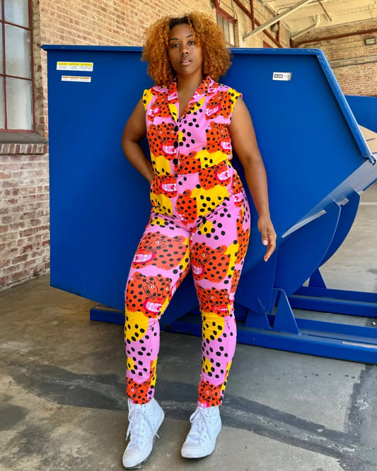 Pink, yellow, and orange tiger Micotti cat print Magic Jumpsuit by Nooworks. Button down closure front and a tapered ankle. Paired with white sneakers.