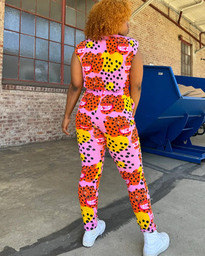 Pink, yellow, and orange tiger Micotti cat print Magic Jumpsuit by Nooworks. Button down closure front and a tapered ankle. Paired with white sneakers.