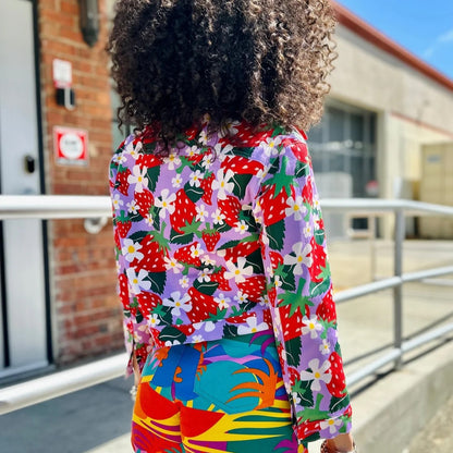 Berries Twill Shorty Jacket by Nooworks. Button-down front and collar neck. Strawberry print in red, green, lilac lavender purple with yellow and white flowers. Floral jacket. Paired with Tropico Twill Summer Shorts.