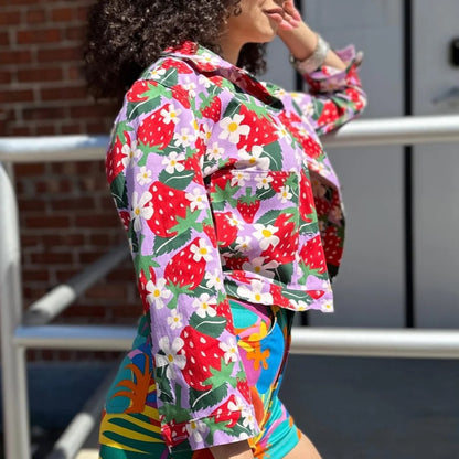 Berries Twill Shorty Jacket by Nooworks. Button-down front and collar neck. Strawberry print in red, green, lilac lavender purple with yellow and white flowers. Floral jacket. Paired with Tropico Twill Summer Shorts.