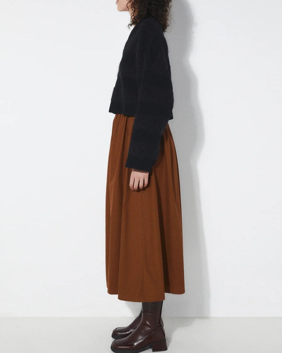 Tobacco brown Fisher Skirt from Rita Row at Clad, a sustainable clothing boutique in Ashevile, NC. Paired with a black v-neck sweater and chestnut leather boots.