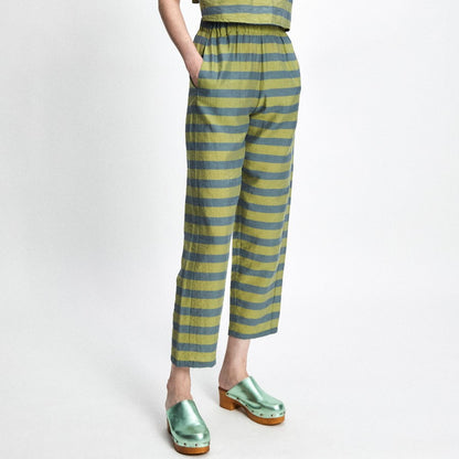 Alternating chartreuse and moss green striped pants with an elastic waist and matching sleeveless top. Cropped and tapered at the ankle. Paired with a shiny mule.