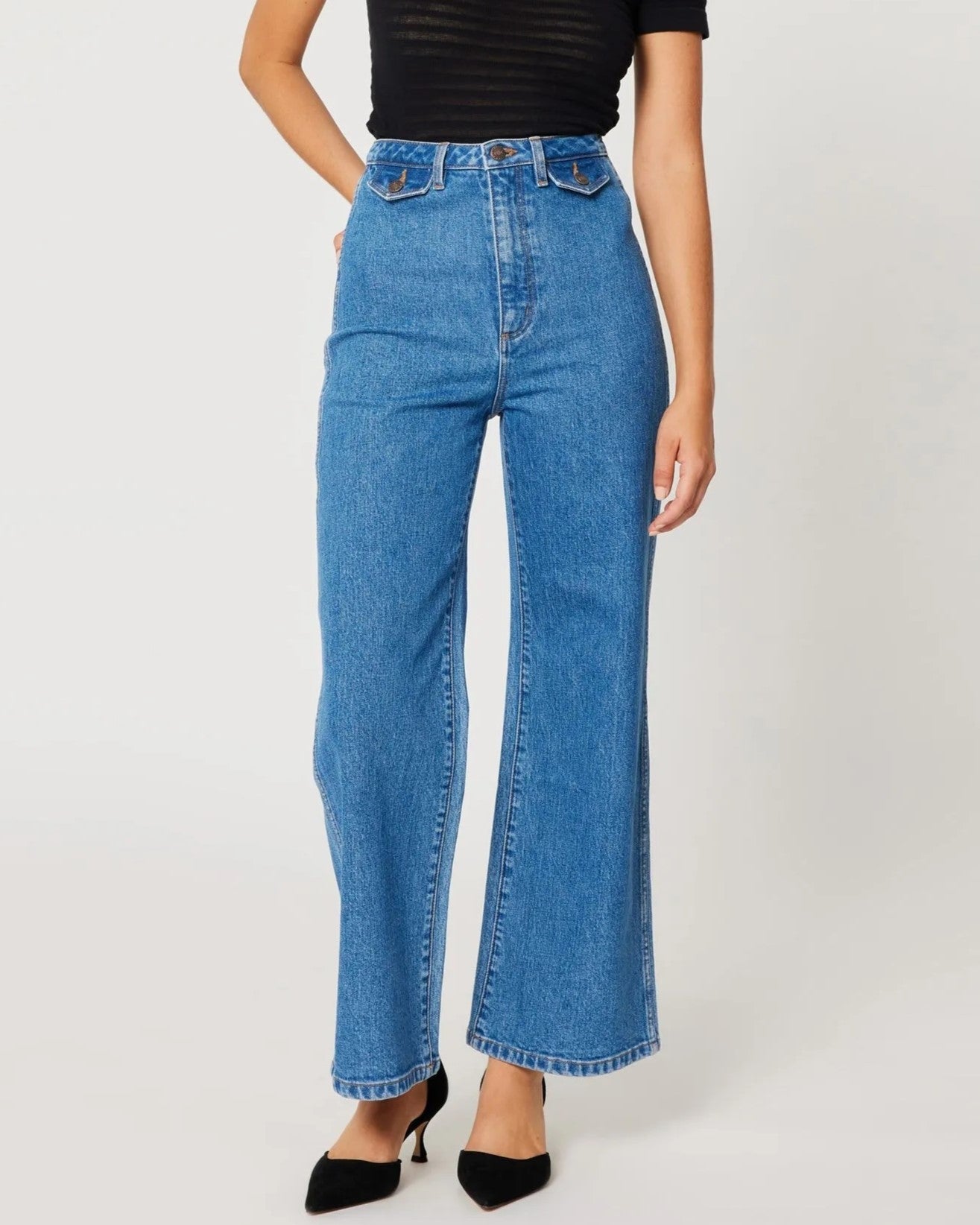 Lia medium blue sailor jeans from Rolla's, high waist with a wider cropped ankle leg. Paired with black pumps and a see-through top.