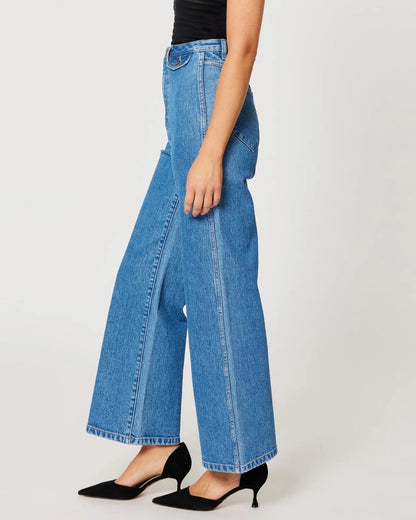 Lia medium blue sailor jeans from Rolla's, high waist with a wider cropped ankle leg. Paired with black pumps and a see-through top.