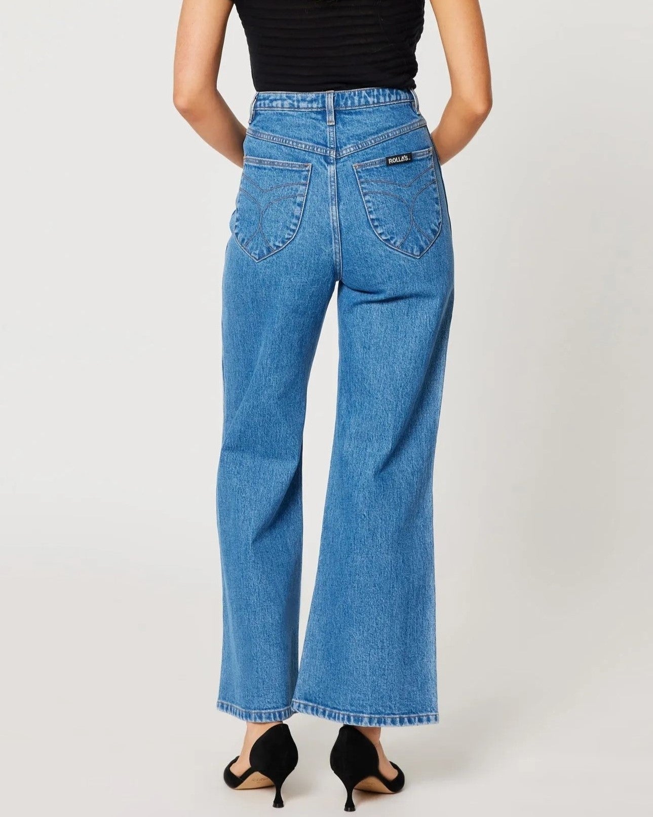 Lia medium blue sailor jeans from Rolla's, high waist with a wider cropped ankle leg. Paired with black pumps and a see-through top.