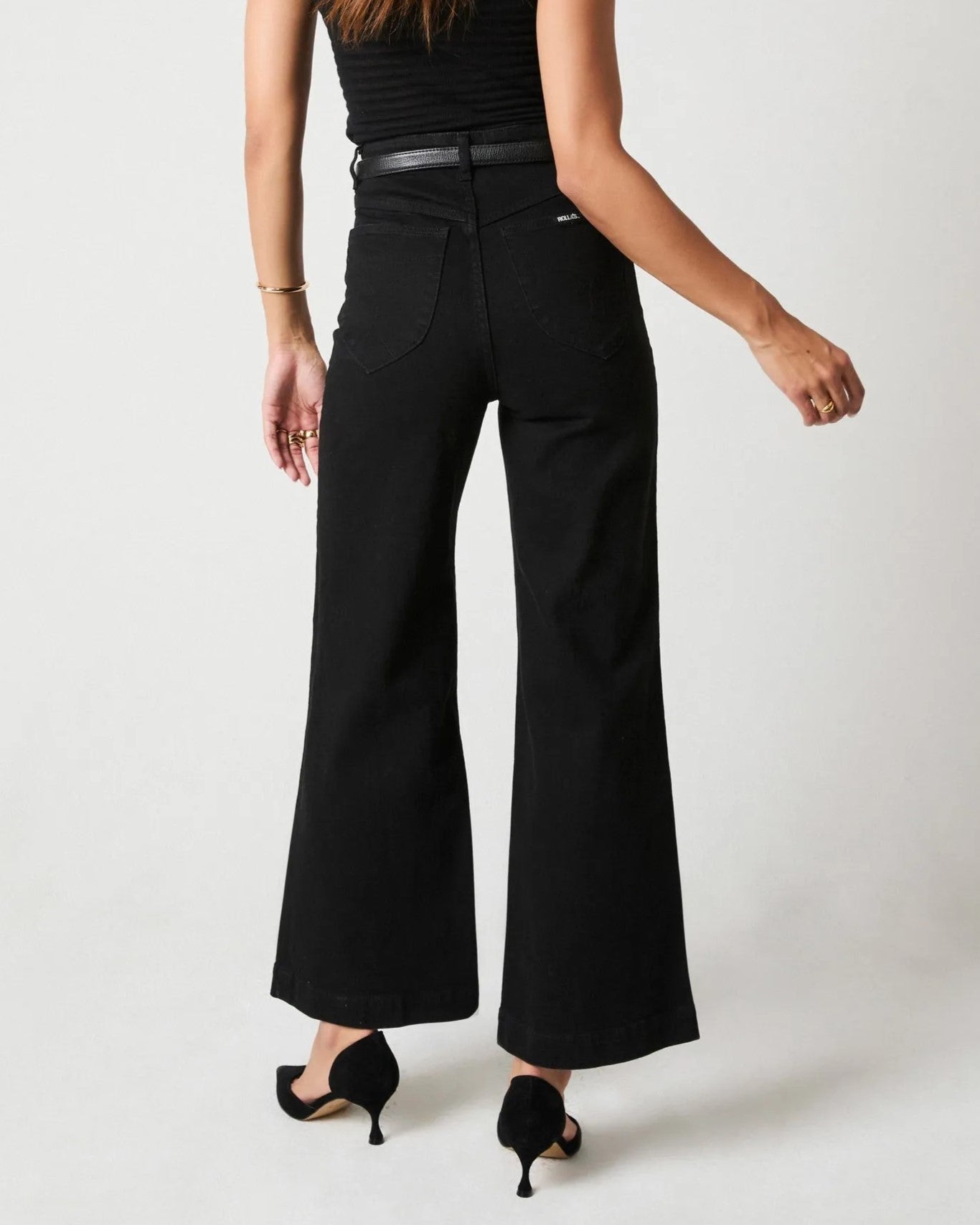 Rinse black sailor jeans from Rolla's, high waist with a wider cropped ankle leg. Paired with black pumps, a see-through top, and a statement belt.