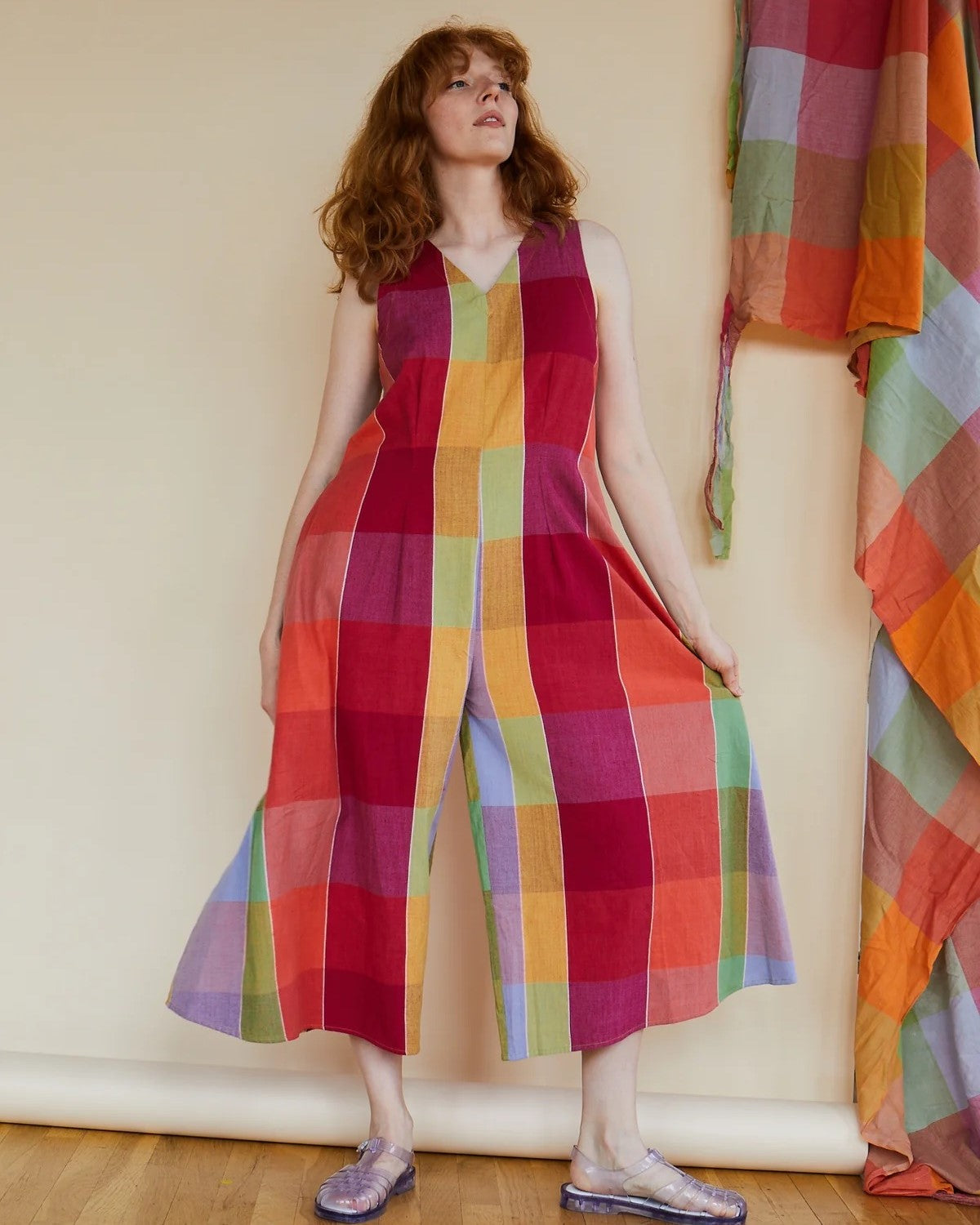 A vibrant, colorful check print patterned jumpsuit with a v-neck, pockets, and zipper back. Made by Rujuta Sheth in India and styled with strappy sandals. Block print in red, orange, pink, yellow, purple, blue, and green.