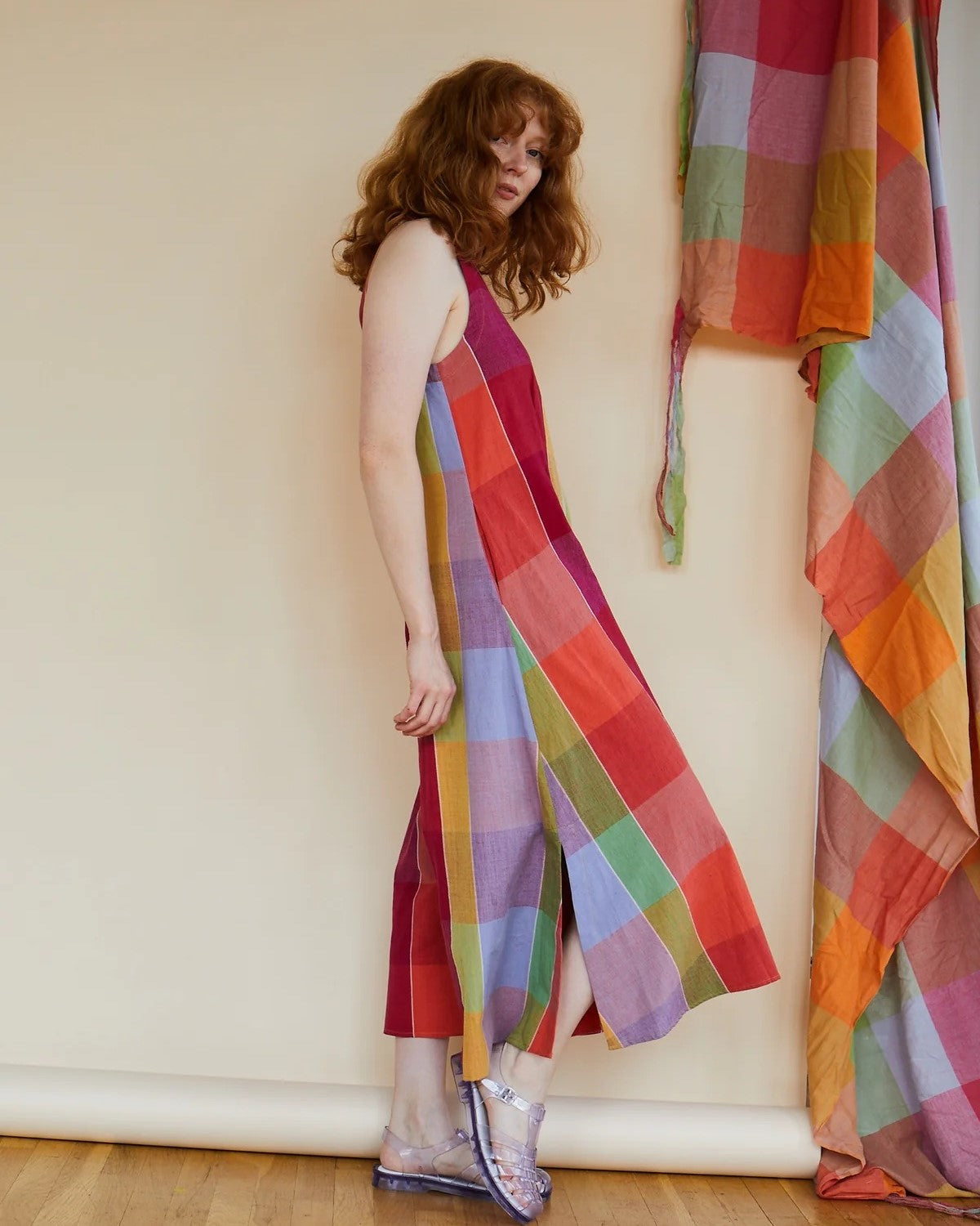 A vibrant, colorful check print patterned jumpsuit with a v-neck, pockets, and zipper back. Made by Rujuta Sheth in India and styled with strappy sandals. Block print in red, orange, pink, yellow, purple, blue, and green.