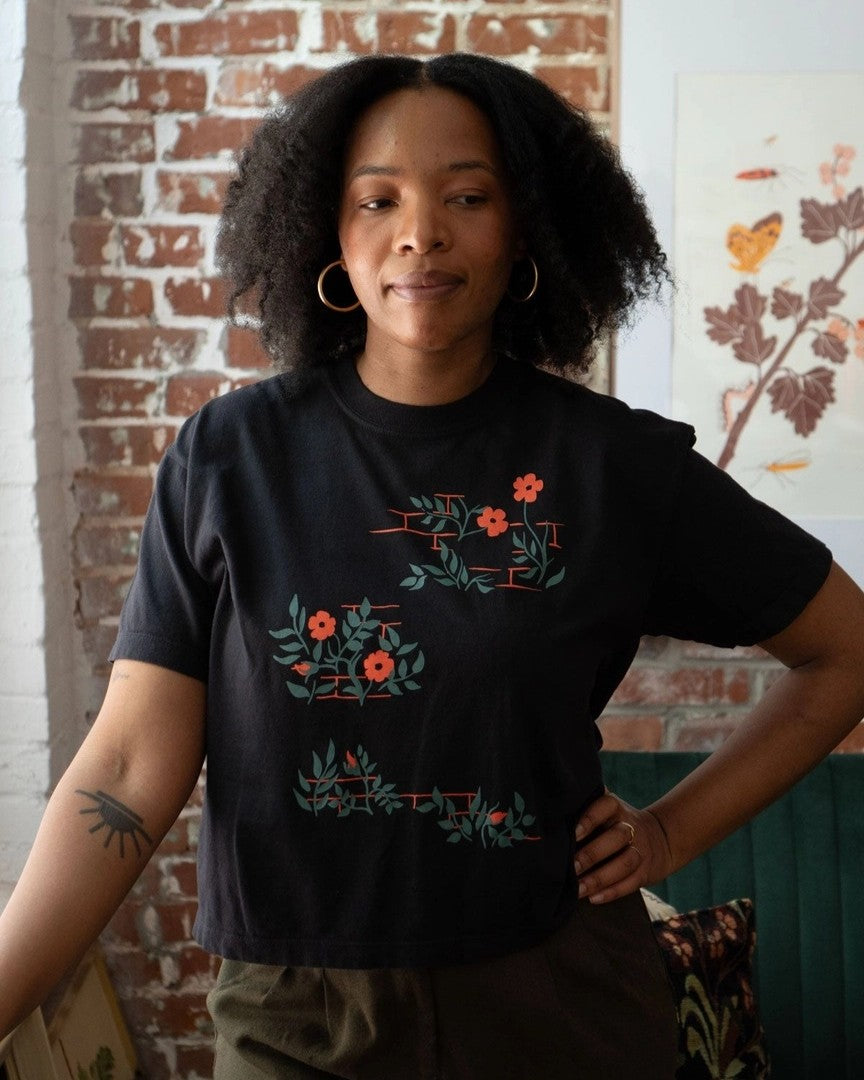 Black floral crop tee from Stay Home Club with green vines and red flowers