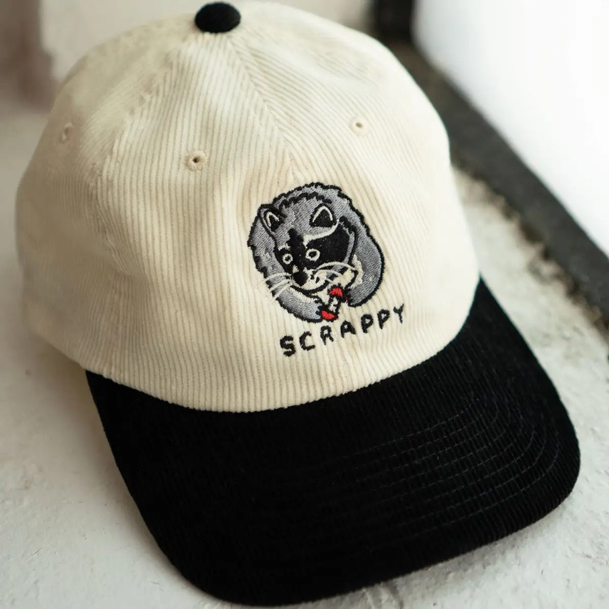 Scrappy raccoon white and black corduroy dad hat by Stay Home Club