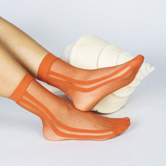 A sheer fishnet orange terracotta striped sock that pairs perfectly with heels, boots, clogs, and more.