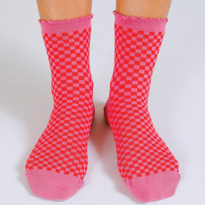 A pink and red checker print sock with scalloped hem.