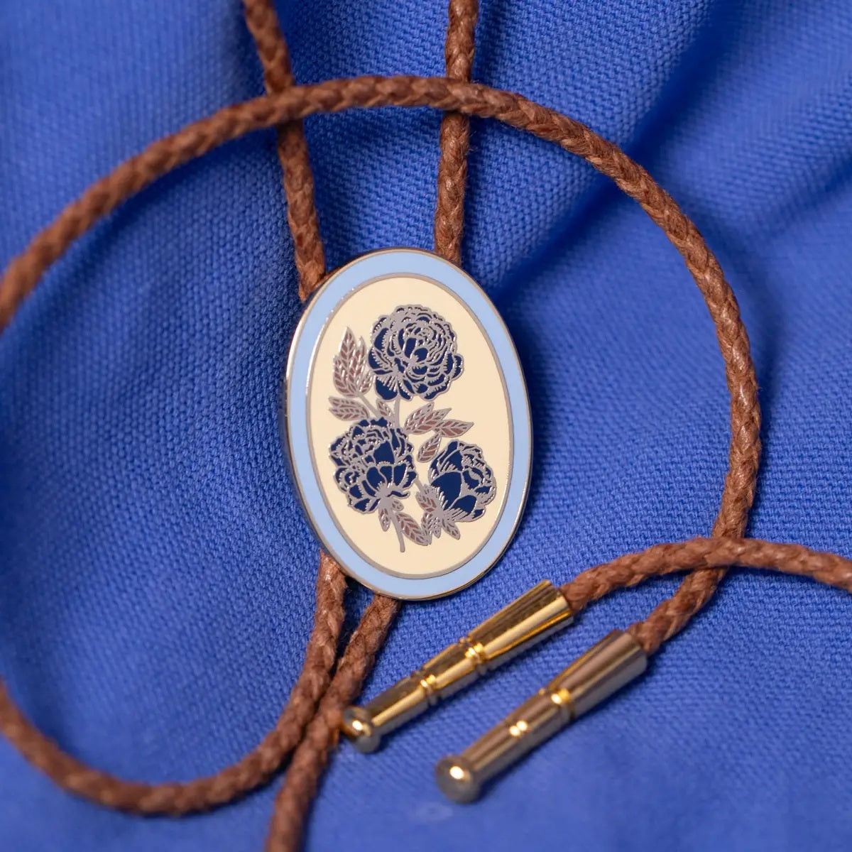 Floral bolo tie with bblue detail and brown vegan leather cord